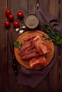 Smoked pork ribs, on a wooden table, top view, sauce, tomatoes and spices, close-up, vertical, no