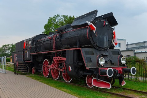 Front view of a black steam locomotive with red details in an open-air museum, Polish steam