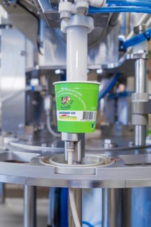Ice cream production with machine that fills green cups, ice cream production Haselstaller Hof,