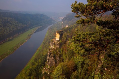 The bright lit Wartturm above the Elbe river seen from the Bastei rocks near the village of Rathen