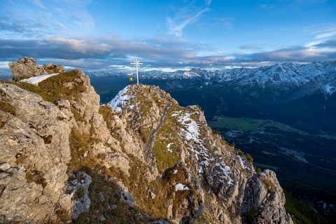Mountaineer at the summit of the Kramerspitz with summit cross, at sunset, in autumn, Ammergau