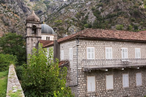 Old two storey stone building with white storm shutters on windows and covered with traditional