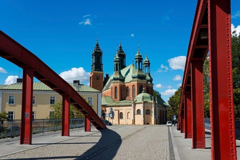 The bridge with red arches leads directly to a historic church with dominating towers, Cathedral,