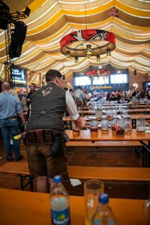 A waiter collects beer mugs from the tables in the marquee, Canstatter Wasen, Stuttgart, Germany,