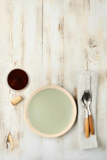 A minimalistic dining arrangement showcases a pale green plate next to a cup of dark beverage,