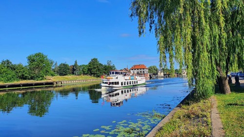 A peaceful river landscape with a boat and overhanging trees, Birkut ship, Elblag River, Elblag,