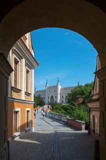View through an archway to a medieval-style castle under a blue sky, view through the Grodzka Tor
