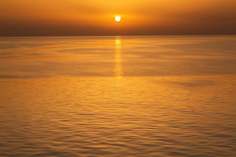 Setting golden sun over Adriatic sea taken from the top deck of a cruise ship in late summer, near