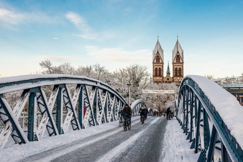 Bridge with snow and ice and cyclists, Blue Bridge and Stühlinger Church, Freiburg im Breisgau,