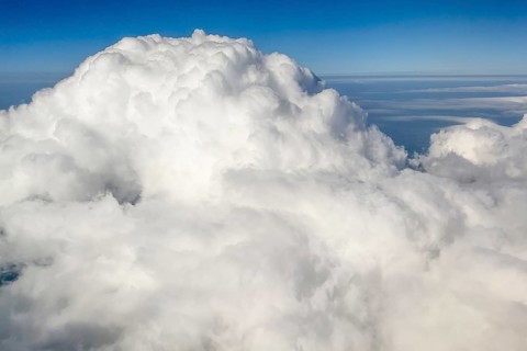 View from at 11887 metres 39000 feet altitude on top dome of large giant white cumulonimbus cloud,