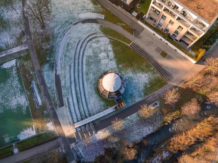 Aerial view of a park with wooden ball in the centre, surrounded by buildings and snow-covered