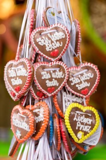 Gingerbread hearts with various love messages and colourful icing decorations, hung on white