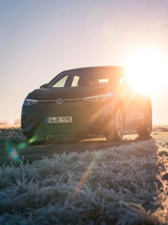 A car parked on a frosted meadow in the low sun, rays of light breaking through, car sharing,