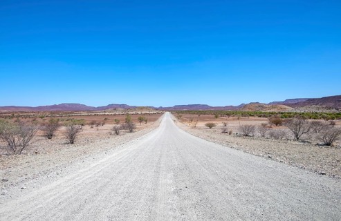 Gravel track leads through barren dry landscape with hills, Damaraland, Kunene, Namibia, Africa