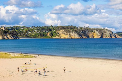 Young people playing volleyball on the sandy beach by the sea on a sunny summer day, Crozon