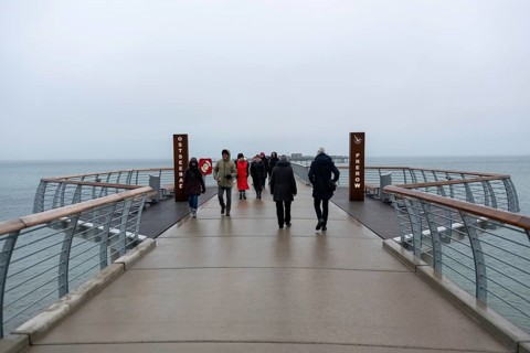 A gloomy day at a pier with several people looking towards the sea, Prerow pier,