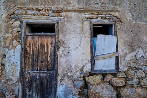 Old, weathered house façade with wooden door and shutters in rustic style, Mesochori village, west