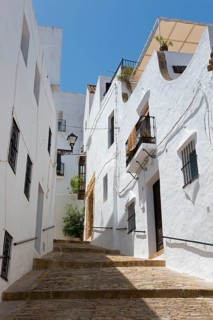 Steep narrow alleyway with white buildings and balconies under a blue sky, Old Town, Vejer de la