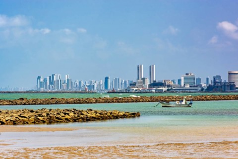 Boat on the beach in the city of Olinda with the skyscrapers of Recife in the background