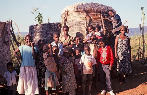 Villagers stand in front of a full maize store in a rural settlement, Malawi, southern Africa,