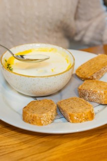 Creamy soup in a bowl with several slices of bread on a plate, autumn creations, Cafe Kuh,