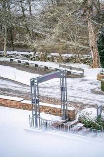 A quiet park in winter with snow-covered paths, trees and an empty bench, spa garden, Bad Wildbad,