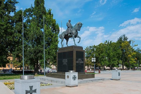 Monumental equestrian statue in a sunny park with surrounding vegetation, monument, equestrian