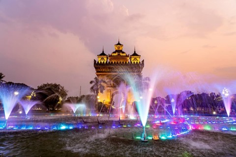 Colourfully illuminated fountain at Patuxai Victory Gate at dusk, capital Vientiane, Laos, Asia