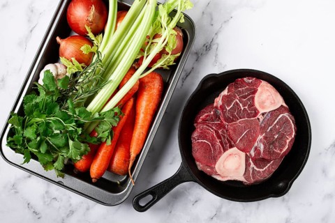 Sknuckle on the bone, raw meat for ossobuco, in a cast-iron pan, baking sheet with vegetables, top