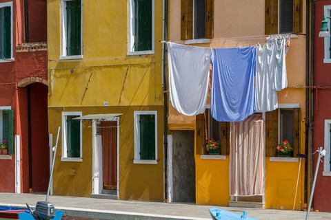 Laundry hangs on a yellow façade, the Mediterranean style creates a cosy atmosphere, Burano,