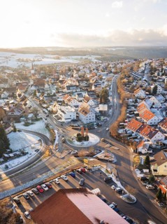 Town with snow-covered roofs and a central roundabout in winter light, Calw- Stammheim, Black