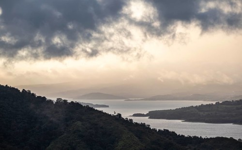 View to the sea over wooded hills, at sunset, cloud forest, Monte Verde, Puntarenas province, Costa