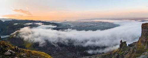 Fog between the cliffs, clouds moving around, glacier ice of the Kötlujökull glacier tongue at