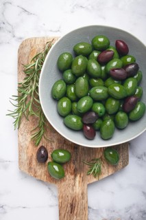 Chalkidiki olives, classic Greek green olives, in a bowl on a cutting board, top view, without