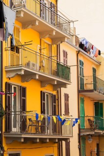 Yellow and beige stucco cladded residential apartment building facade and washed clothes drying on