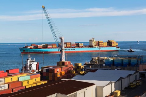 Maersk Serangoon cargo ship loaded with metal box shipping containers being guided by pilot boats