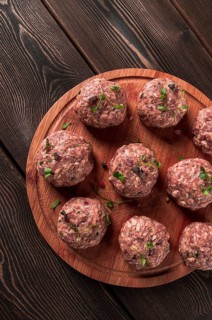 Raw meatballs, with micro greenery, on a cutting board, homemade, rustic, no people