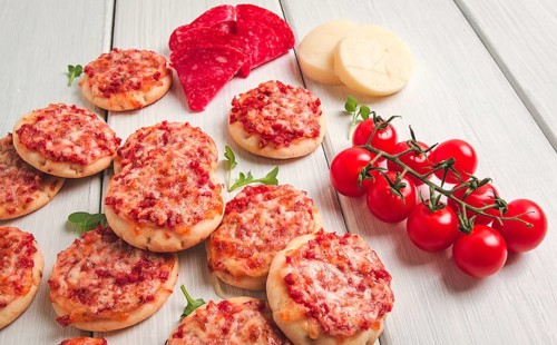 Mini pizzas, salami with mozzarella cheese, on a white table, top view, no people