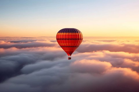 Colorful hot air balloon floats over a sea of clouds at sunset at sunset with orange and blue skies