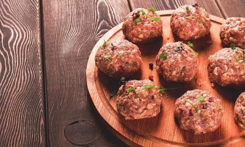 Raw meatballs, with micro greenery, on a cutting board, homemade, rustic, no people