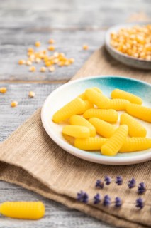 Jelly corn candies on gray wooden background and linen textile. close up, side view, selective