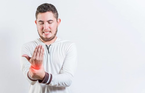 Person with arthritis pain rubbing hand isolated. Suffering young man with pain in hand joints