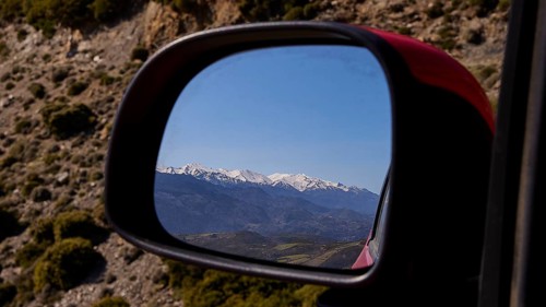 Mountain landscape in winter, reflected in the car mirror during a car journey, Lefka Ori, White