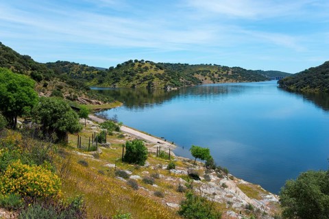Calm river with green hills under a clear sky, peaceful landscape, confluence of the River Tiétar