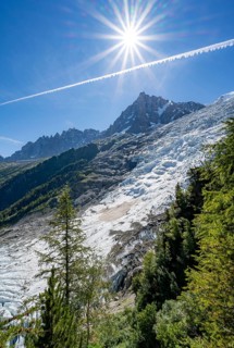 View of glacier Glacier des Bossons with sun star, behind summit of Aiguille du Midi, Chamonix,