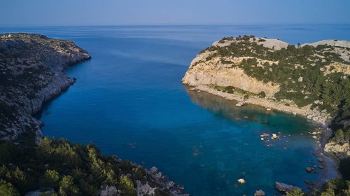 Drone shot, A picturesque, calm bay with crystal clear water and steep cliffs, surrounded by