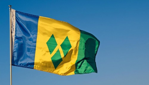 The flag of the Grenadines flutters in the wind, isolated against a blue sky