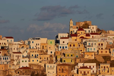 Cycladic architecture on a hill with a central church, warm light dominates the scene, Colourful