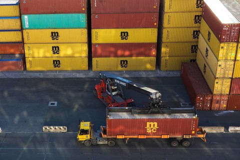 Kone Cranes container handler loading rectangular metal box shipping container onto transportation
