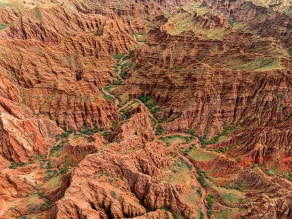 Eroded mountain landscape, top-down, canyon with red and orange rock formations, aerial view,